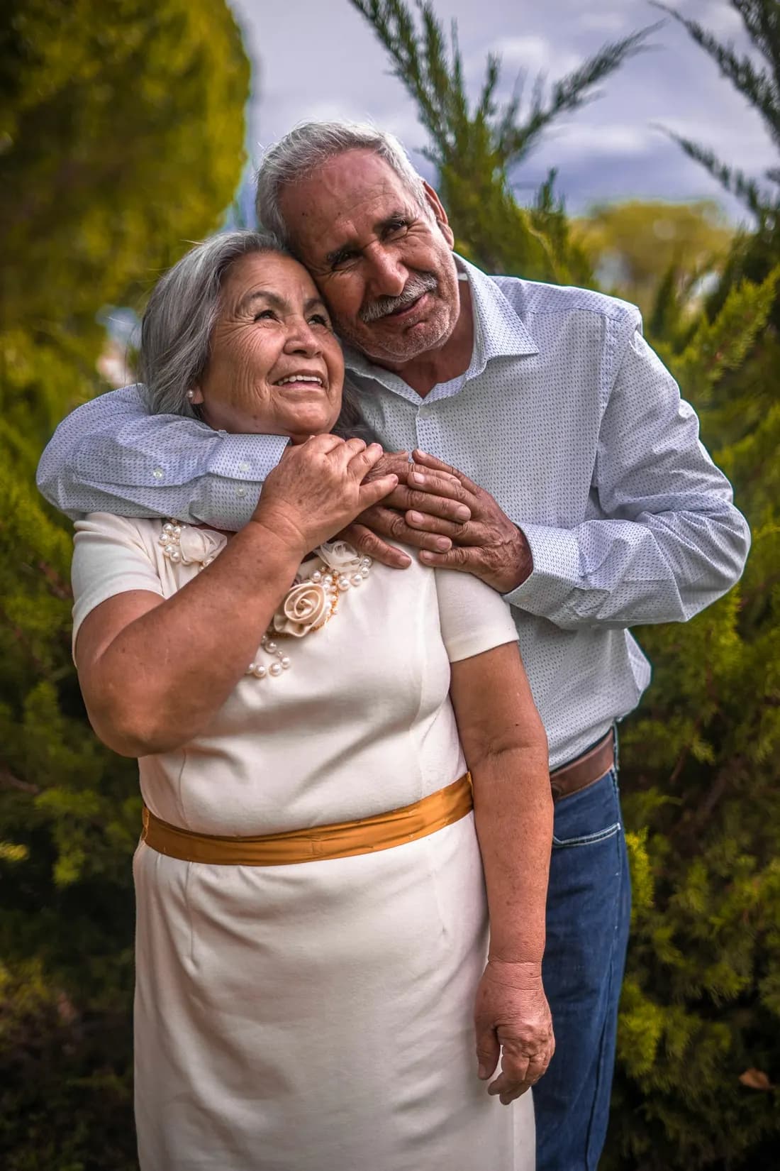 Una pareja mayor se abraza sonriendo al aire libre